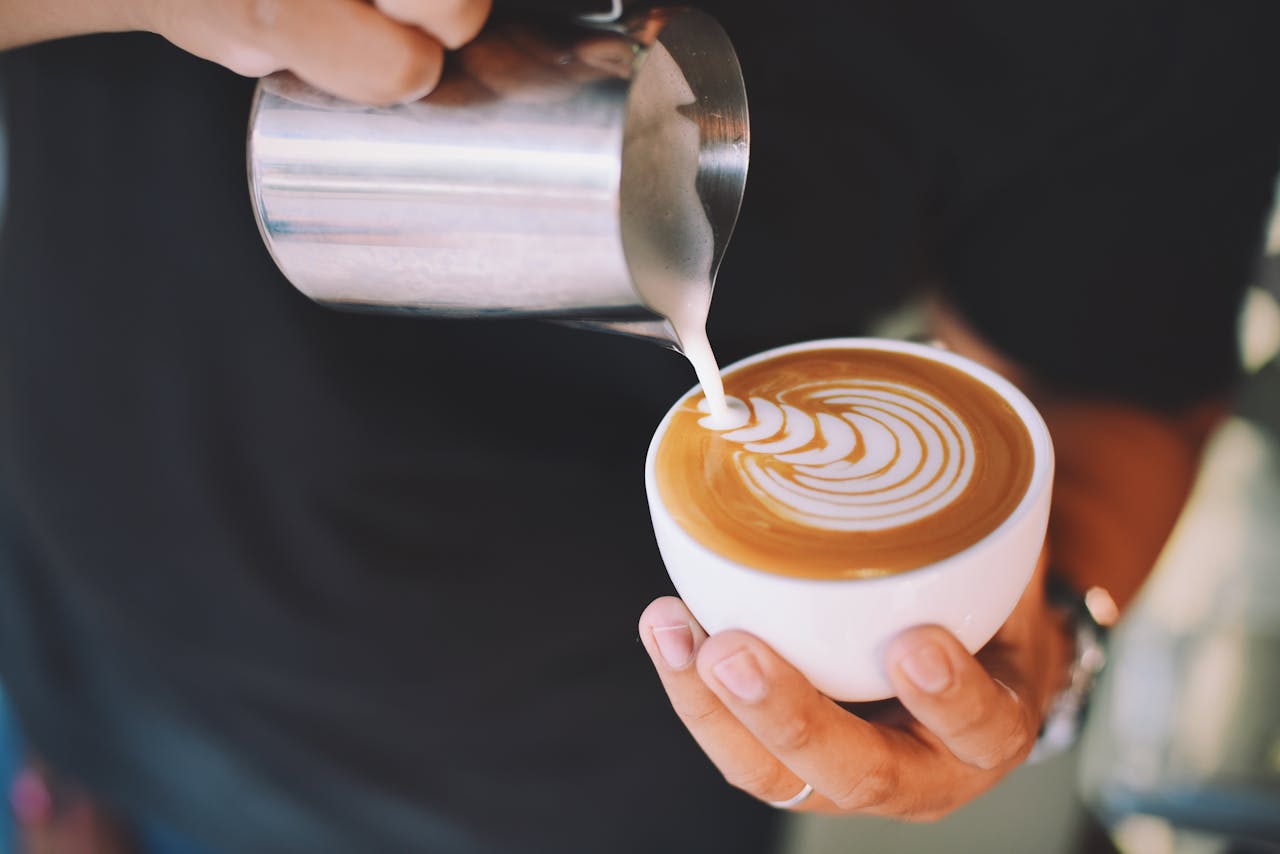 about-us Captivating image of a barista pouring milk art into a cappuccino cup, showcasing latte art skills.